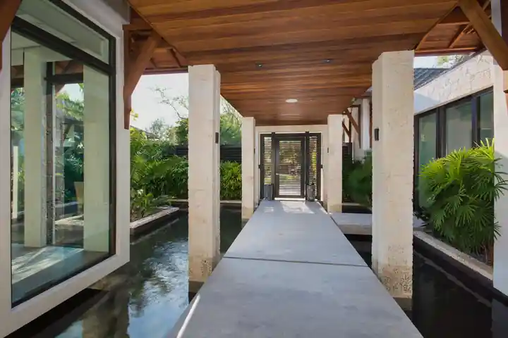 Entry bridge over a reflecting pool lined with planters at a Cutler Bay residence