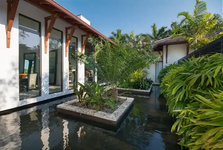 Reflecting pool with a planted island along the windows of a Cutler Bay residence