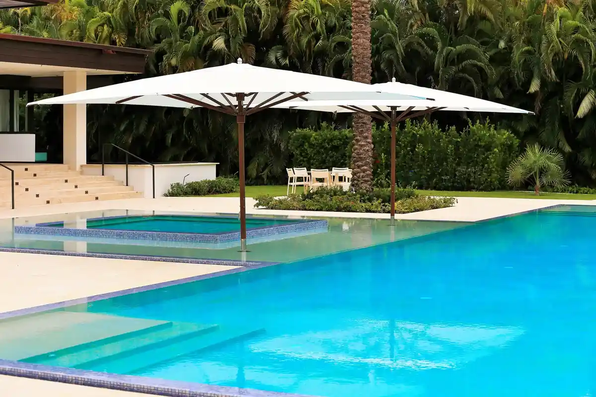 Bright pool with a raised spa and white umbrellas on a stone deck in Gables Estates