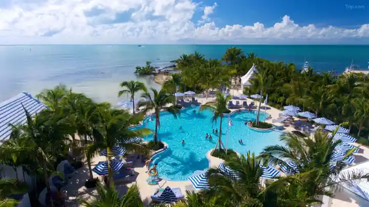 Aerial of the freeform lagoon pool at Isla Bella Beach Resort with striped umbrellas and the ocean behind