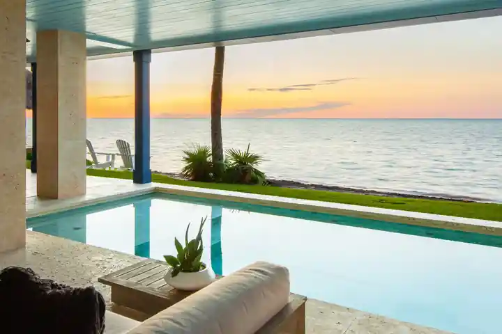 Covered pool terrace opening onto the ocean at sunset at an Islamorada residence