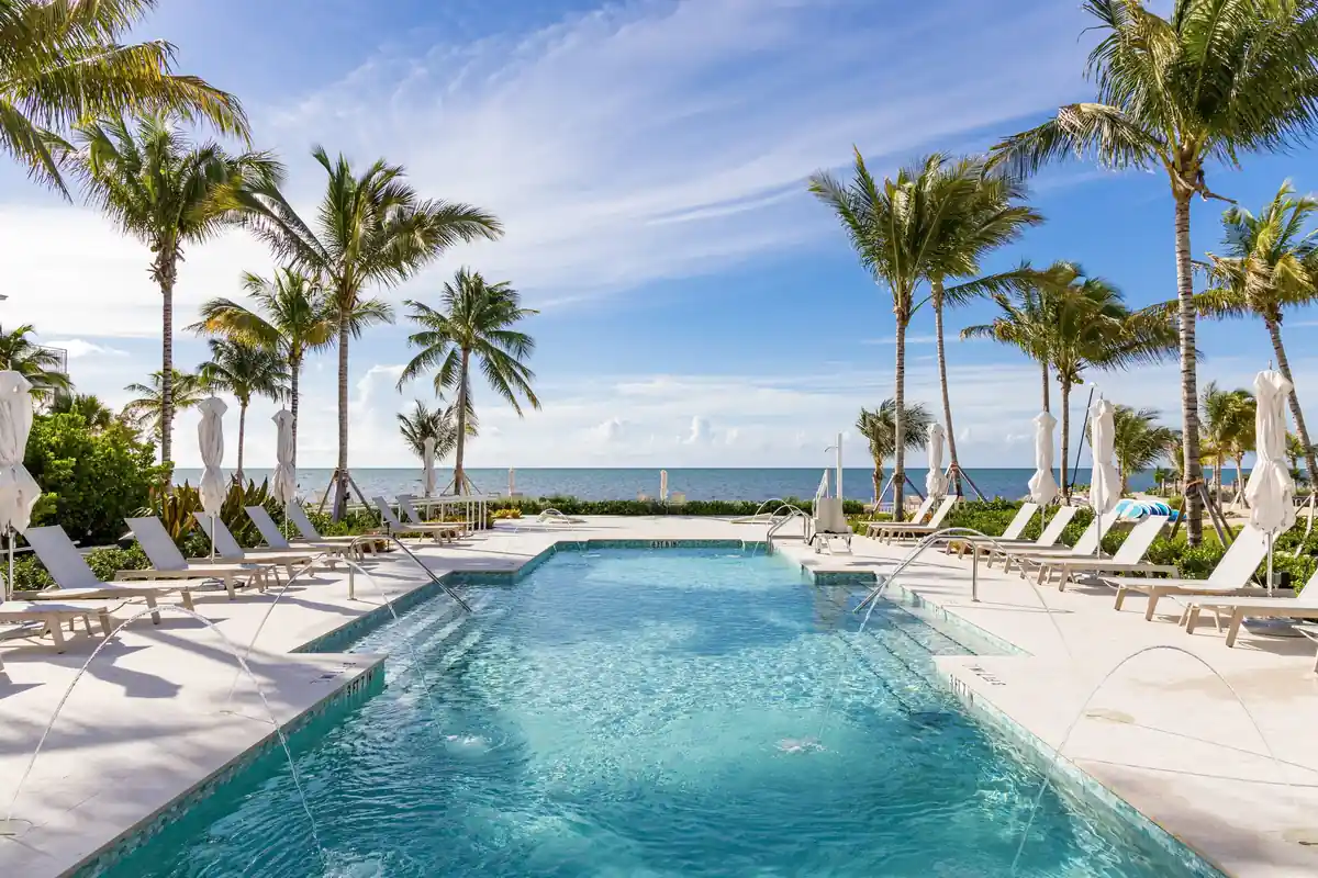 Rectangular resort pool with stepped entry and white loungers facing the ocean at Islands of Islamorada