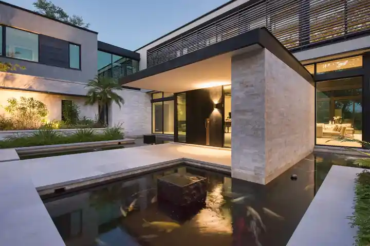 Koi pond under a cantilevered modern house entry at dusk at Journeys End