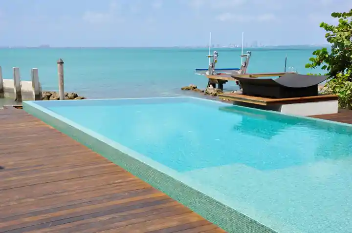 Glass tile infinity pool and teak deck with the bay and skyline beyond on Key Biscayne
