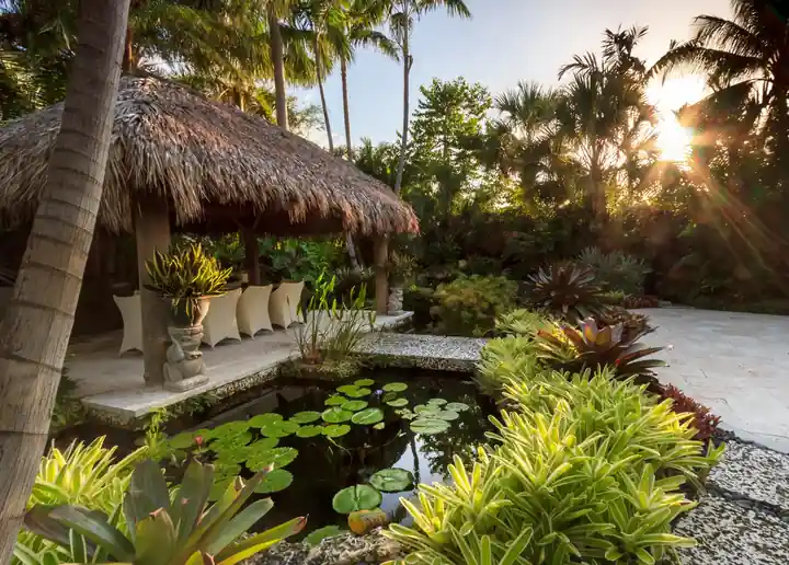 Koi pond with lily pads beside a thatched cabana in a Key West garden