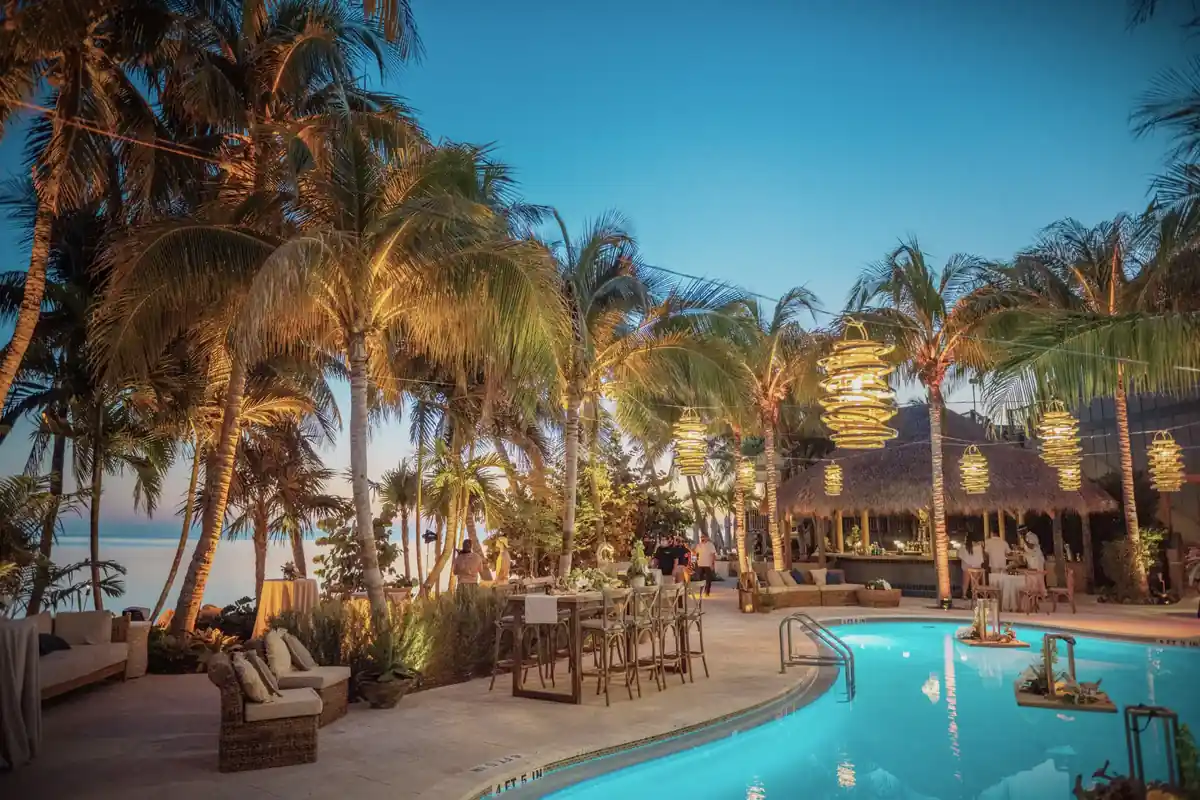 Freeform resort pool at dusk under lantern-hung palms at Little Palm Island