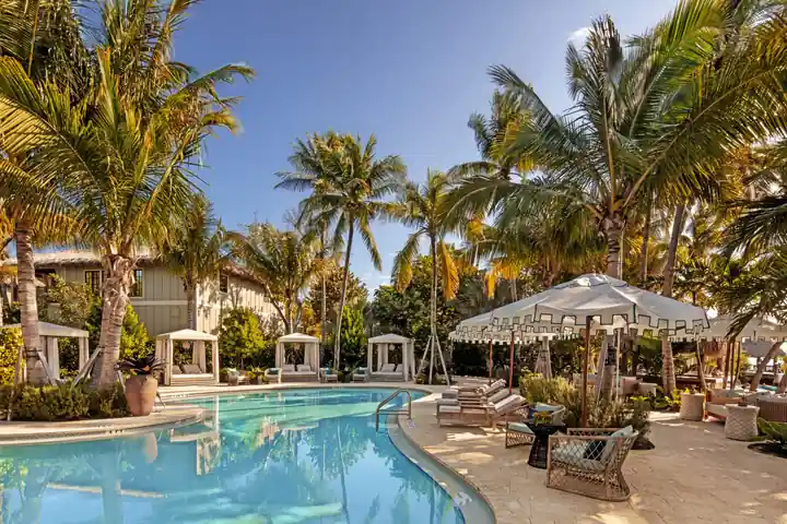 Curving resort pool with cabanas and palms at Little Palm Island
