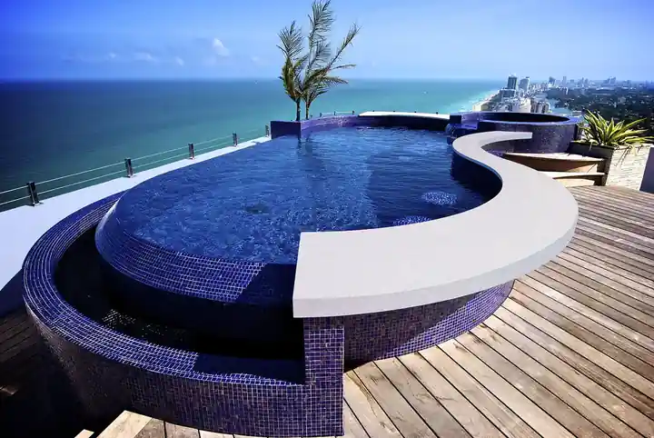 Curved rooftop spa in blue glass mosaic with the ocean and Miami Beach towers behind