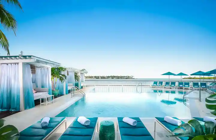 Rooftop resort pool at Ocean Key Resort with white cabanas, teal loungers and the water beyond