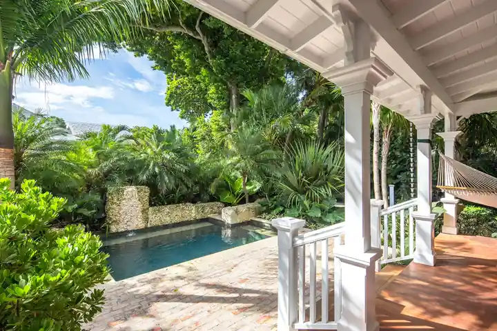 Small pool framed by a white porch and tropical planting in Old Town Key West