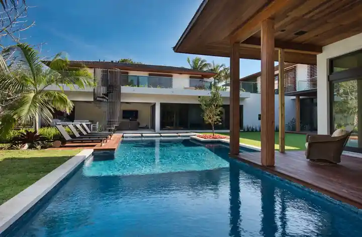 Residential pool with a teak deck pavilion and a modern two-storey house in South Miami