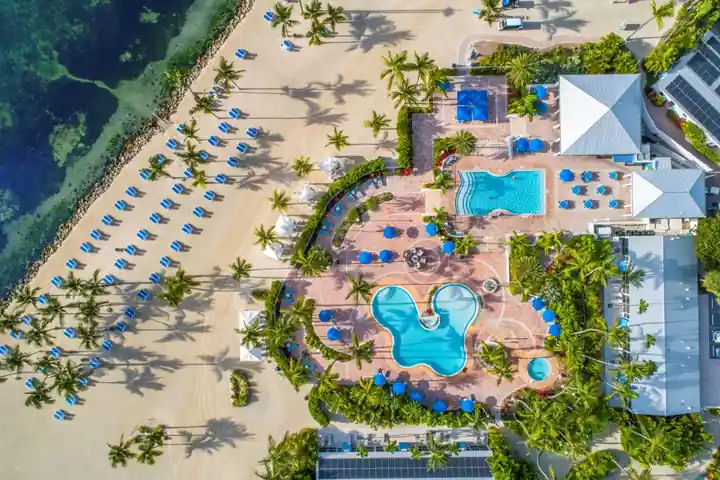 Aerial of The Islander resort pools beside the beach, rows of loungers on the sand