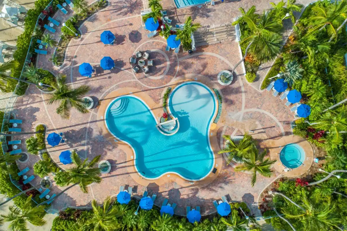 Aerial view of two freeform lagoon pools and a spa set in a paver deck at The Islander, Islamorada